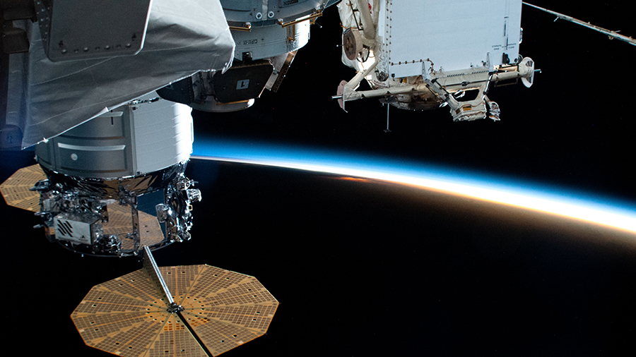 The space station with the Cygnus spacecraft attached (left) orbits 261 miles above the Pacific Ocean into a sunset.